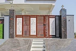 Una entrada protegida por un portón decorativo, con escalones que conducen a él y una cámara de seguridad en lo alto.