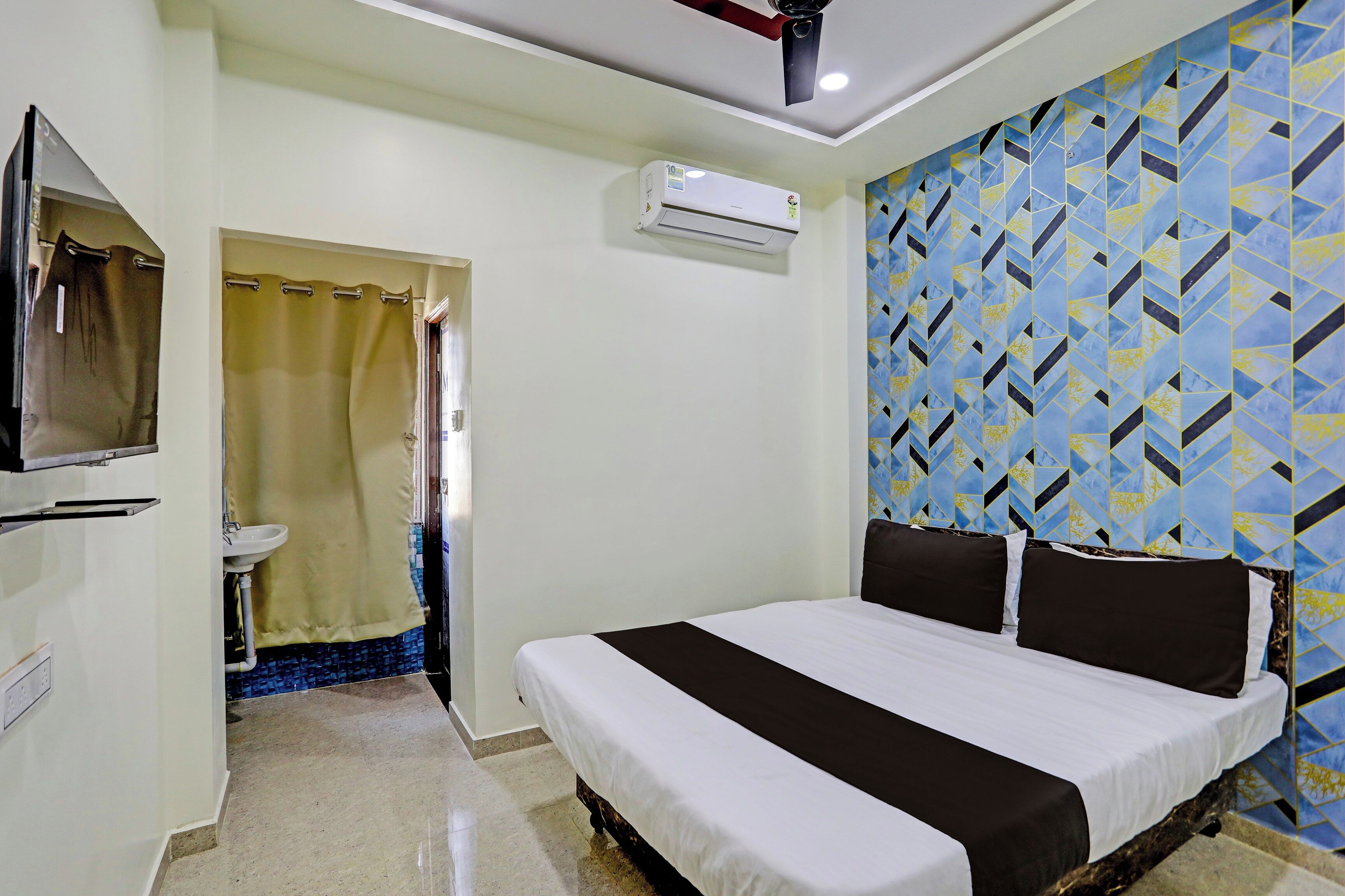 A hotel room with a bed, a bathroom with a sink, and a shower.
