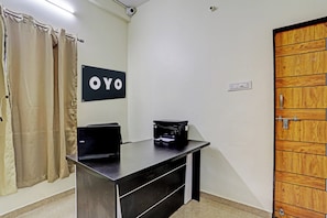Una habitació amb escriptori, ordinador, impressora, una porta i un rètol amb la paraula 'OYO'.