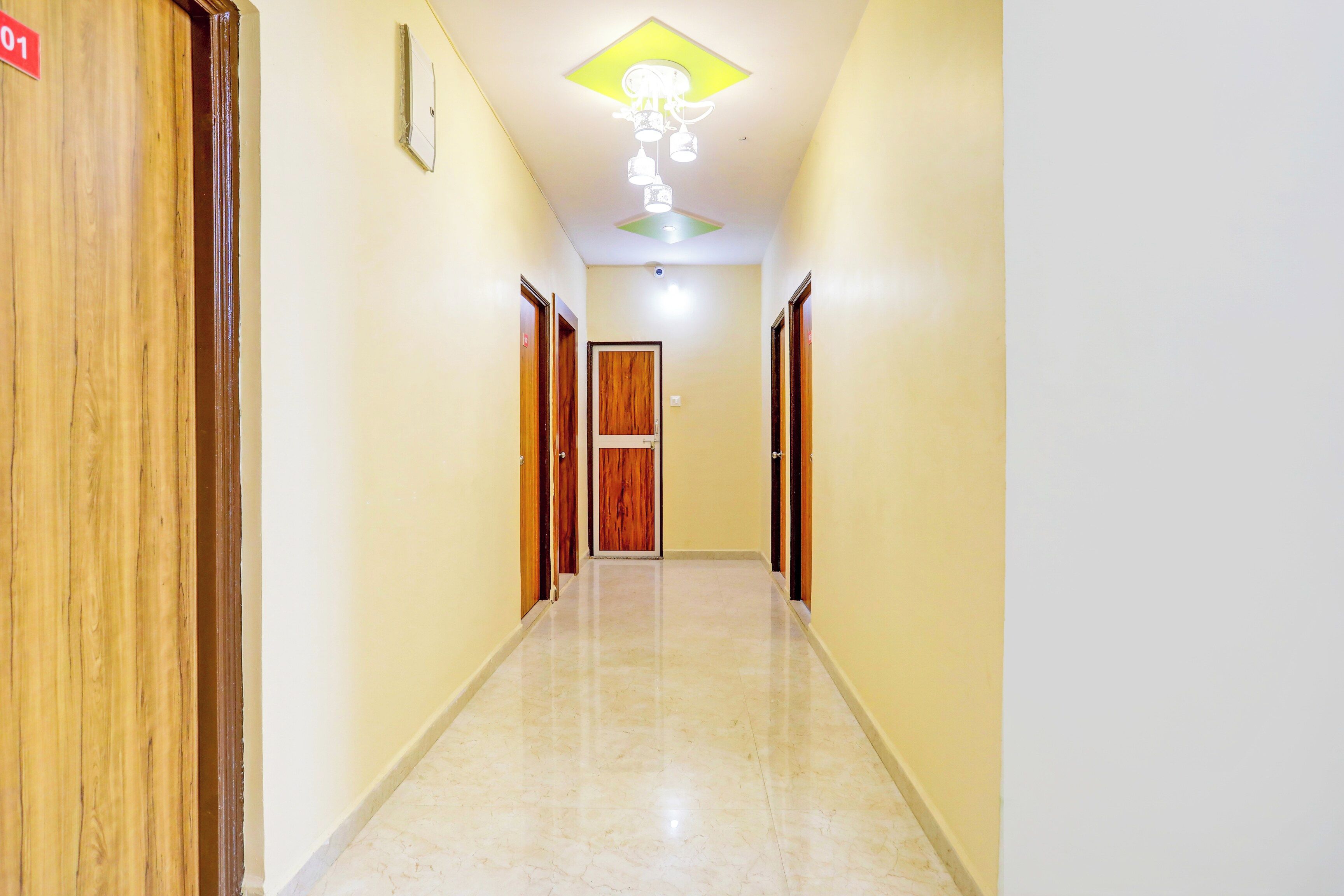 Un couloir avec des portes en bois, un luminaire au plafond et un sol carrelé.