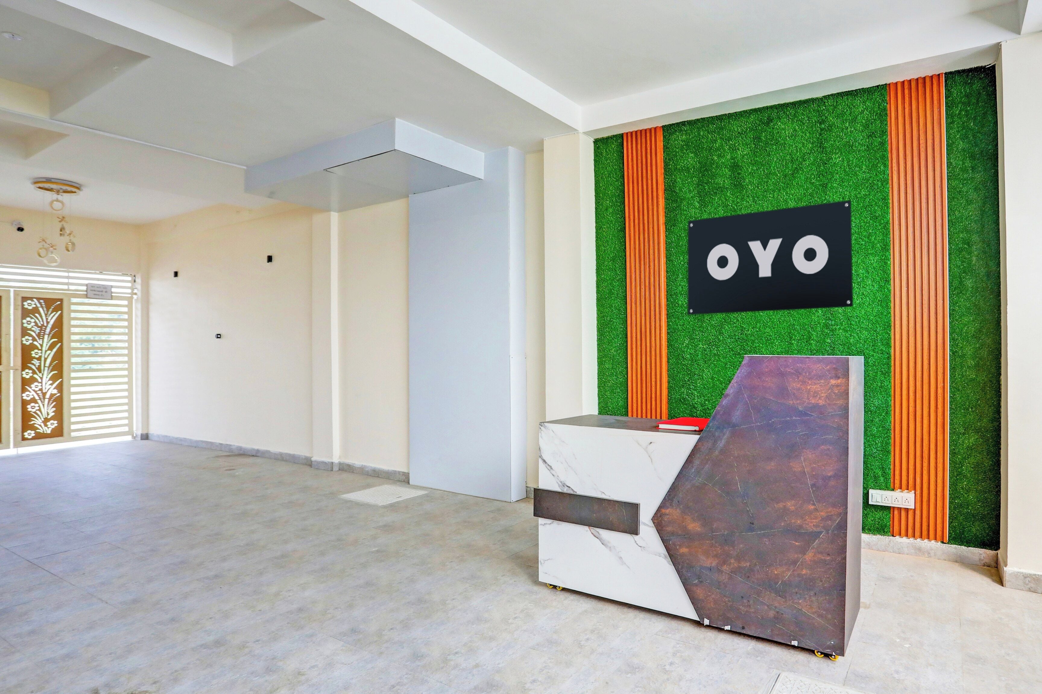 A reception area with a marble counter, a sign reading 'OYO', and a green and orange wall.
