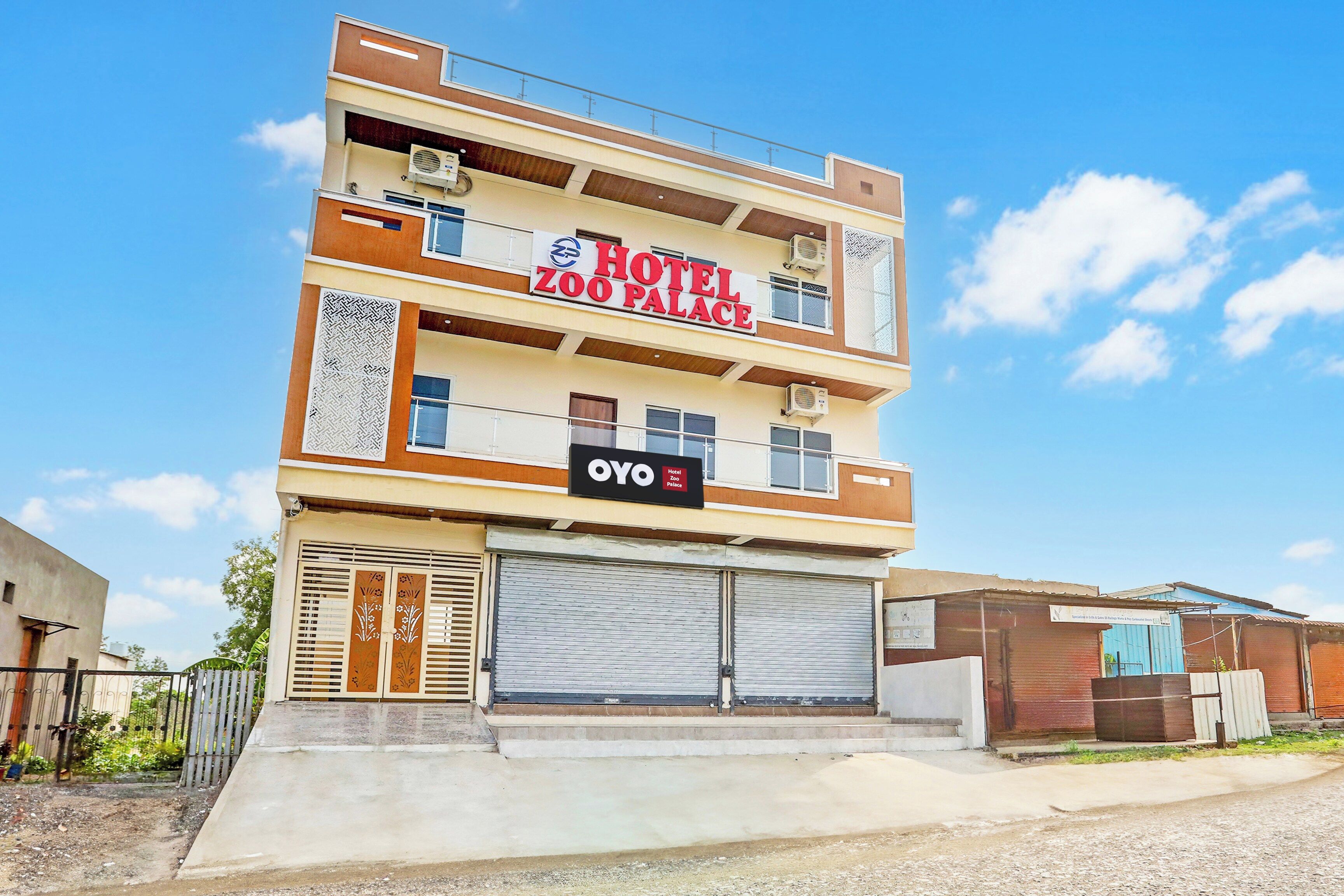 A multi-story building with a sign for 'HOTEL ZOO PLACE' and a smaller sign for 'OYO HOTEL ZOO PLACE'.