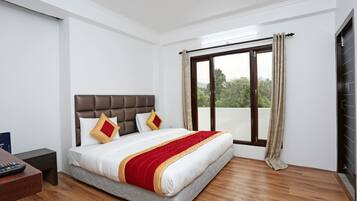 Habitación de hotel con una cama grande, suelo de madera, vistas a la vegetación por la ventana y un diseño moderno.