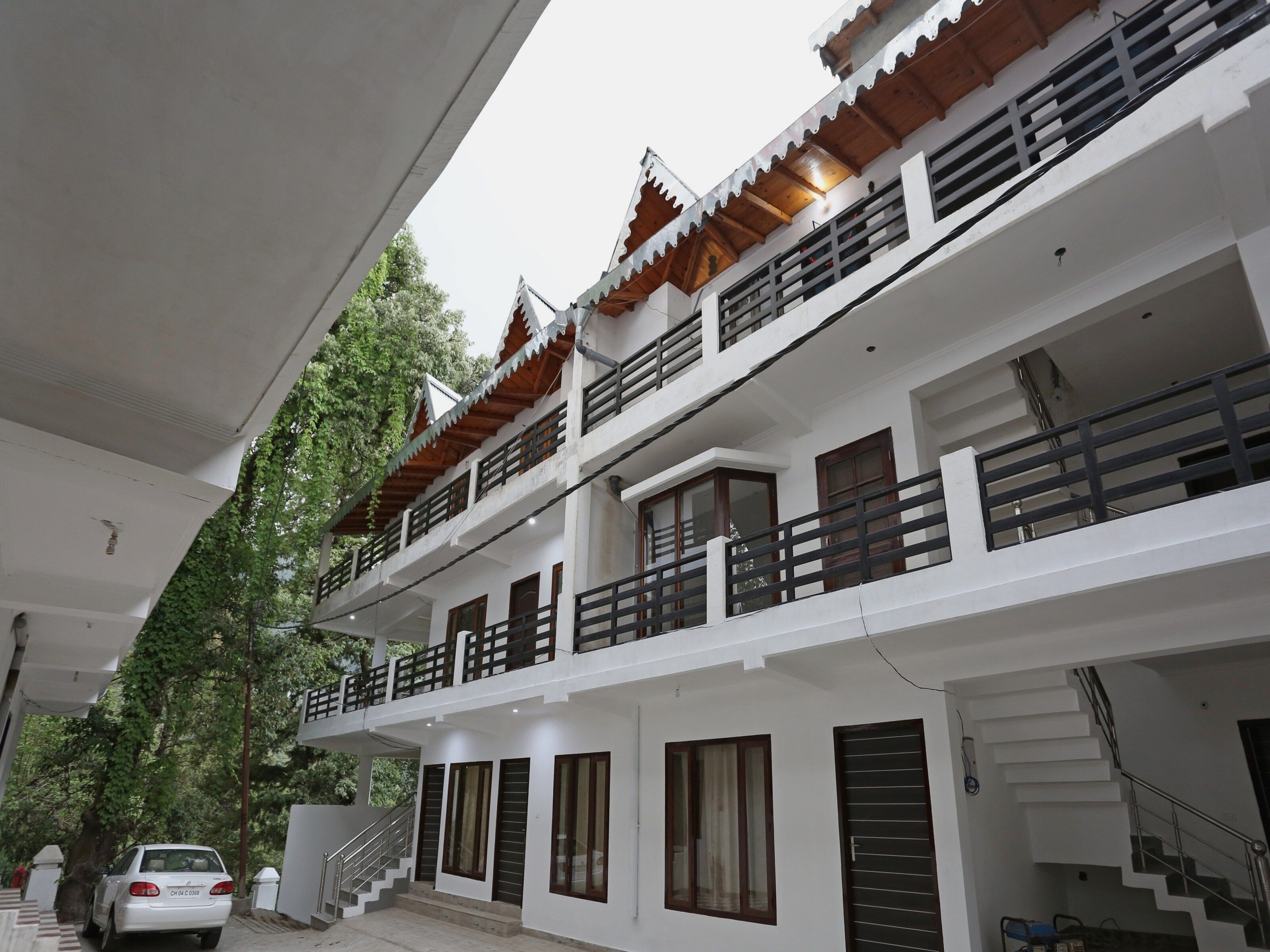 Un edificio de varios pisos con fachada blanca, balcones con barandillas de madera y una escalera que conduce a los pisos superiores.