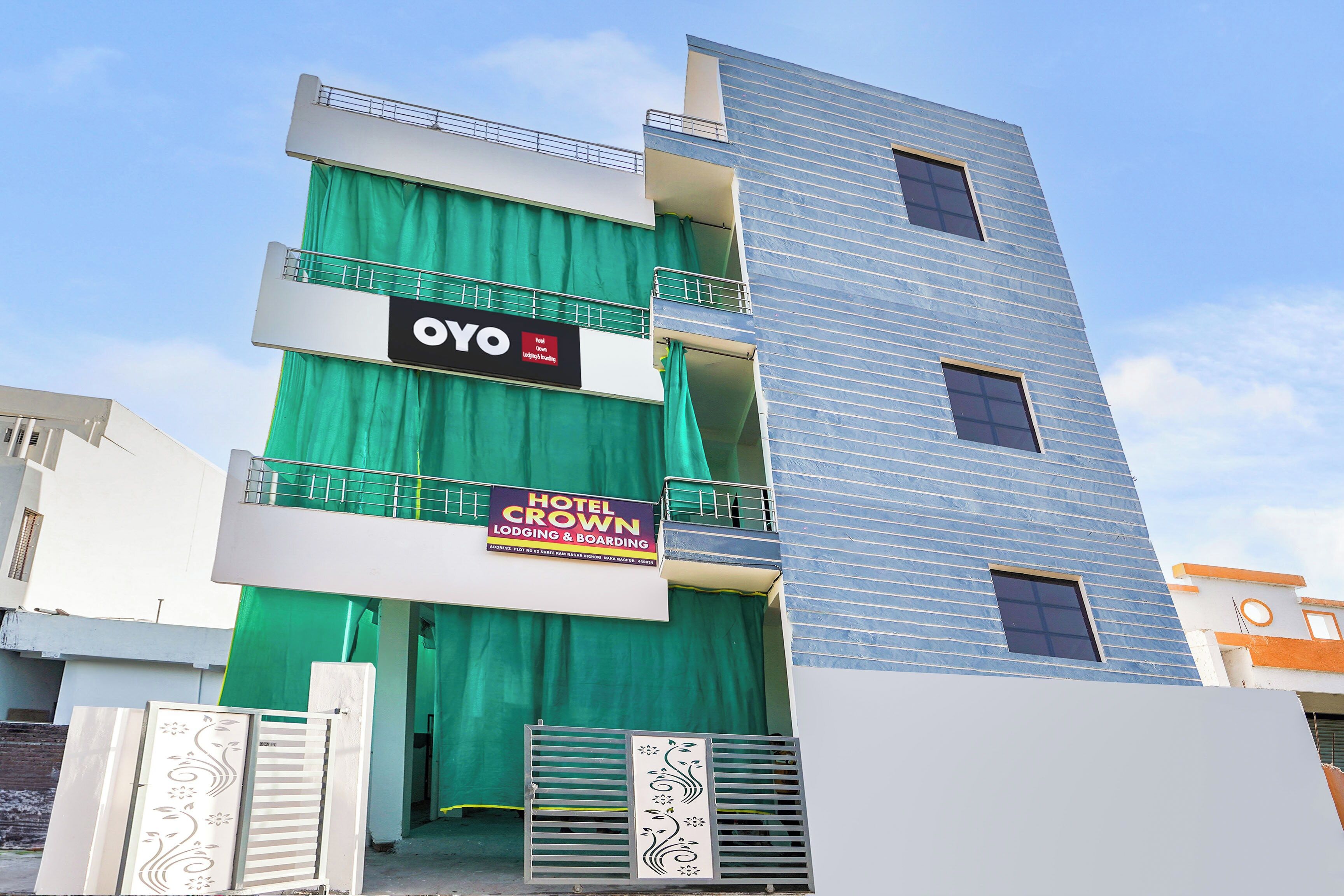 A multi-story hotel with a green curtain entrance, balconies, and a sign for 'Hotel Crown Lodging & Boarding'.