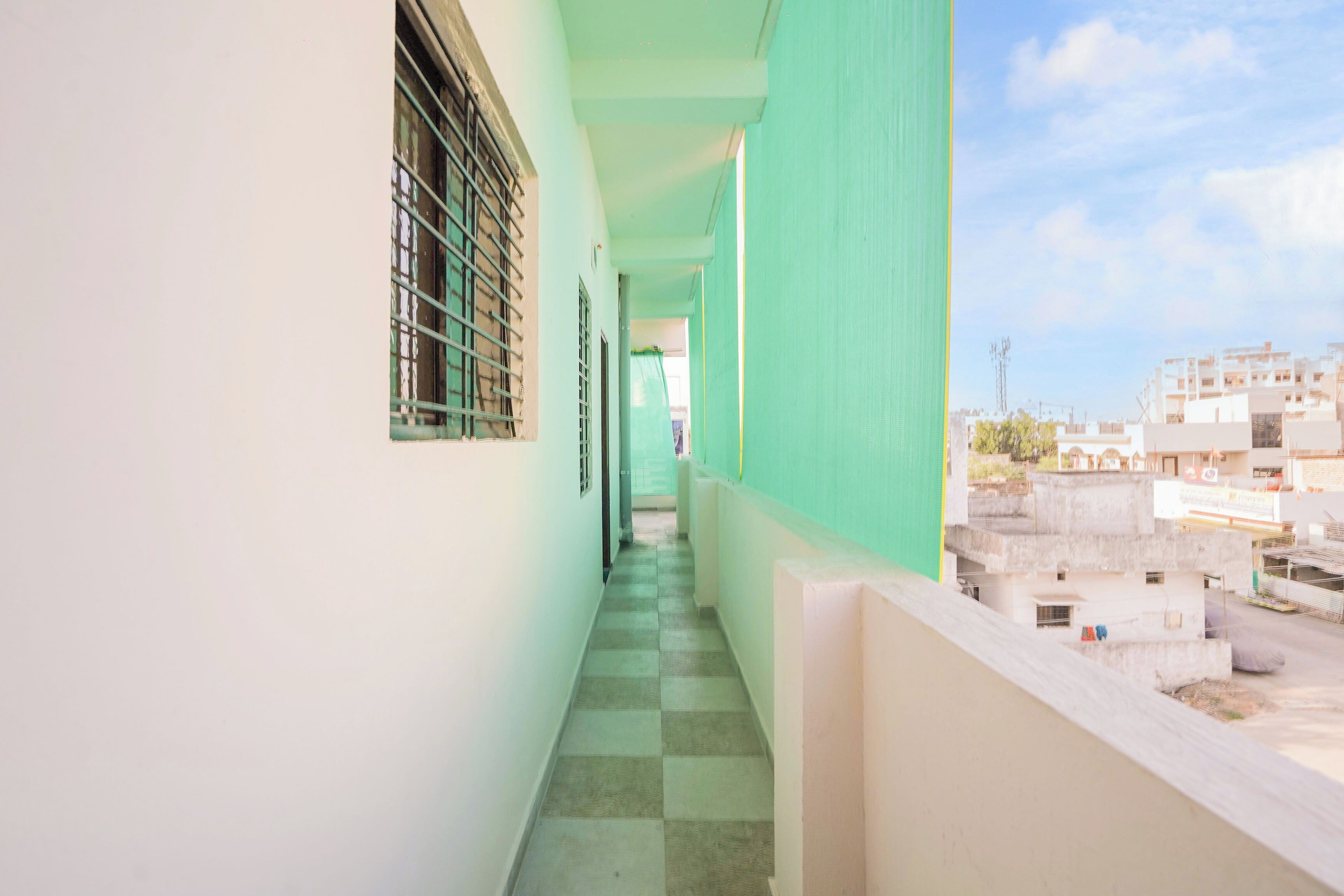 A corridor with a checkered floor, a window with bars, and a view of buildings in the distance.