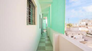 A corridor with a checkered floor, a window with bars, and a view of buildings in the distance.