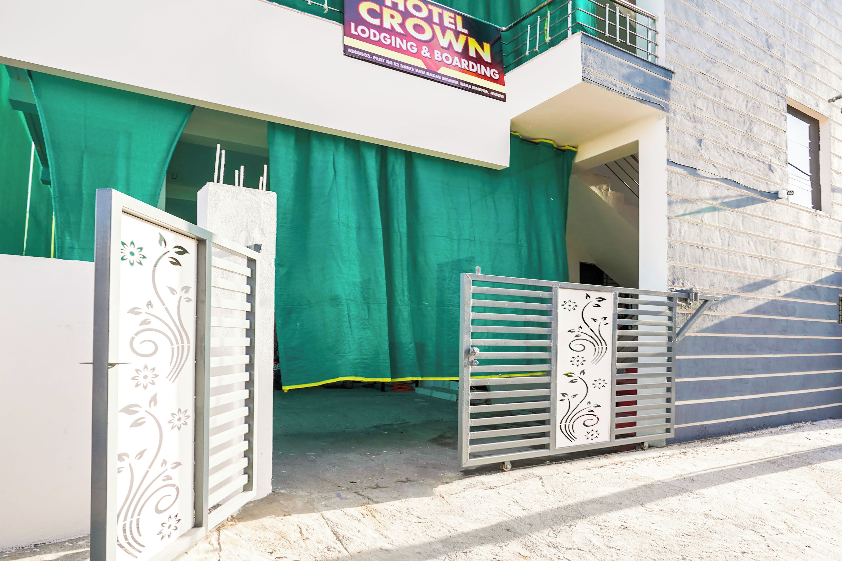 Entrada de hotel con cortina verde, letrero y puertas decorativas.