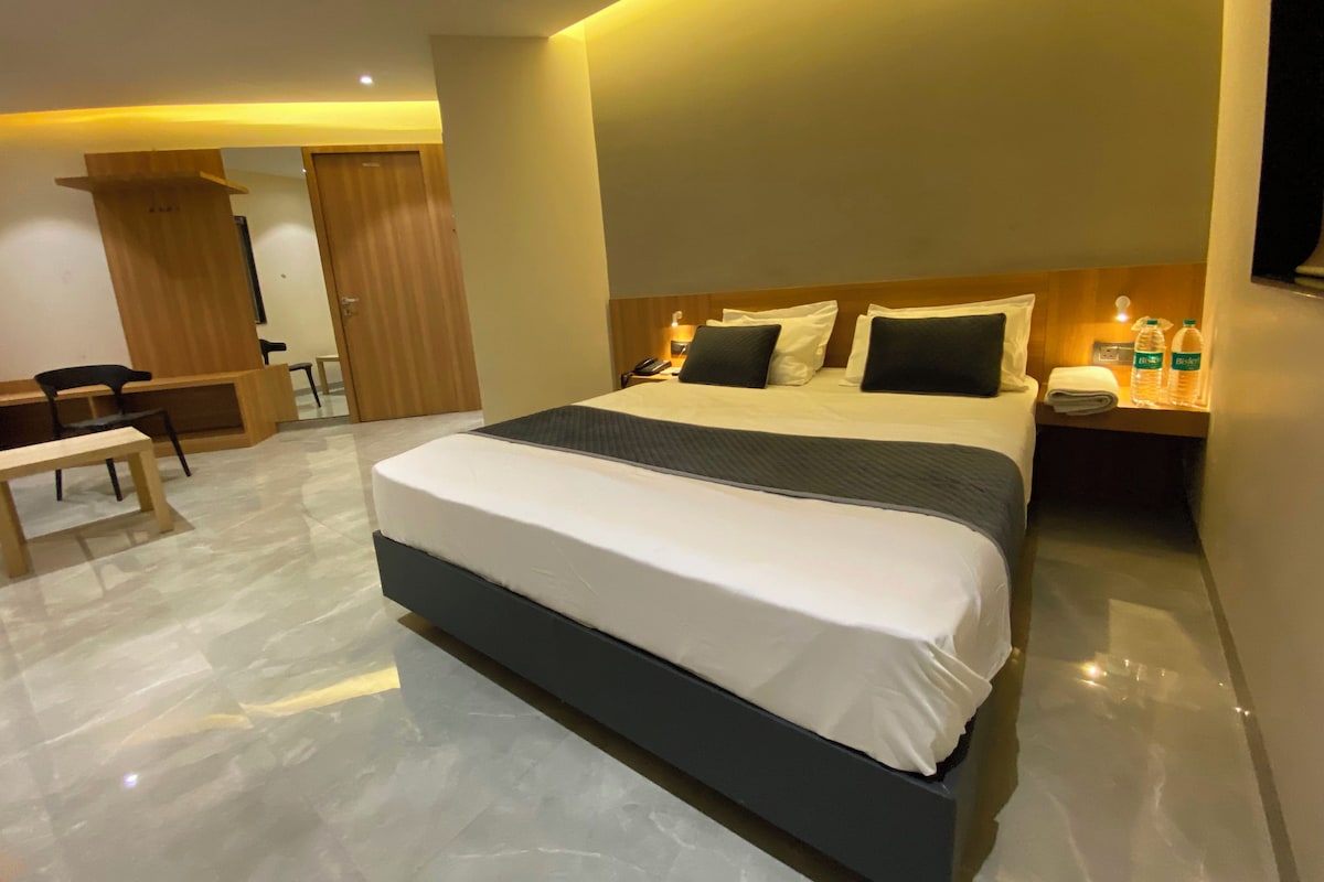 Une chambre d’hôtel moderne, dotée d’un grand lit, de tables de chevet, d’un bureau et d’une chaise.