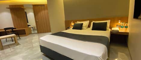 A modern hotel room with a large bed, bedside tables, a desk, and a chair.