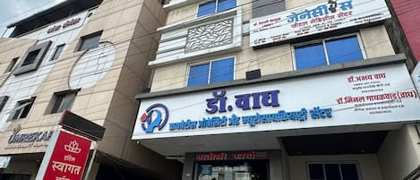 A multi-story building with various signs, including one for a hospital and another for a dental clinic.