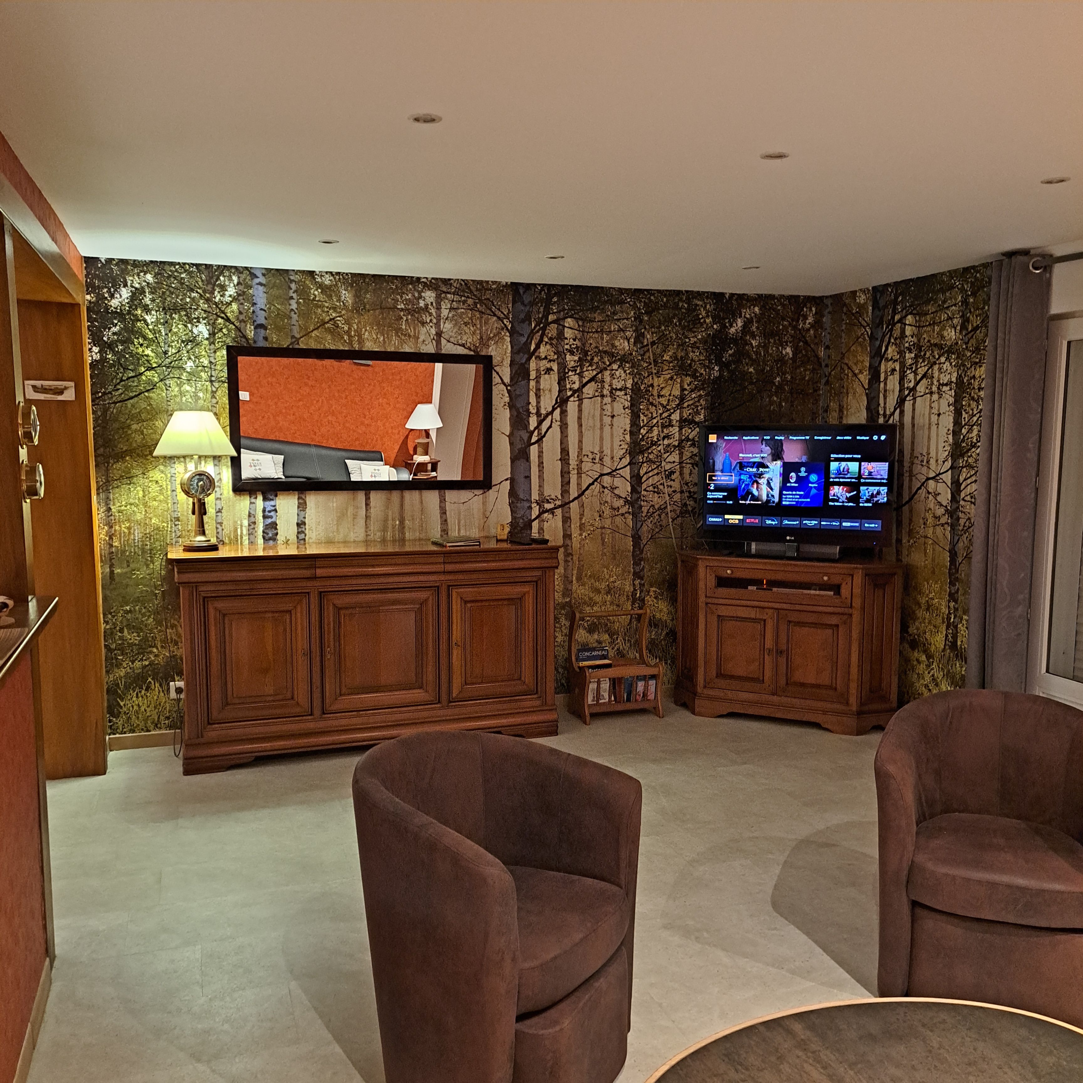 Una sala de estar con un televisor de pantalla plana, armarios de madera y dos sillones marrones.
