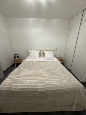 Une chambre d’hôtel avec un grand lit, deux tables de chevet et une armoire.