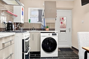 A compact kitchen with a stove, oven, sink, and a washing machine. - Serene 3-bedroom apartment in the heart of Manchester (Manchester)