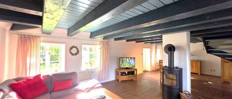 Een woonkamer met een bank, televisie en een houtkachel.
