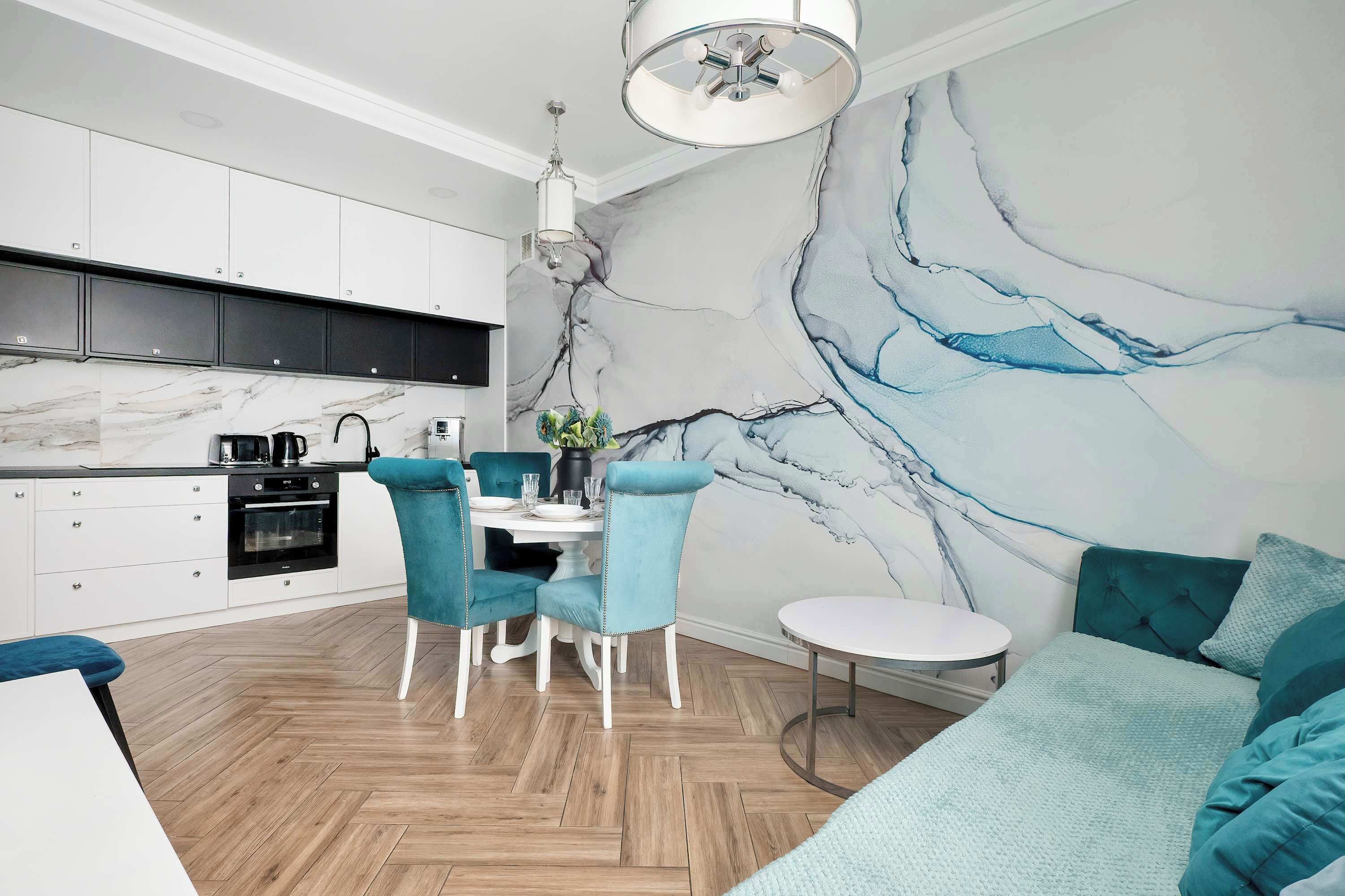 A modern kitchen with white cabinets, a black countertop, and a marble backsplash.