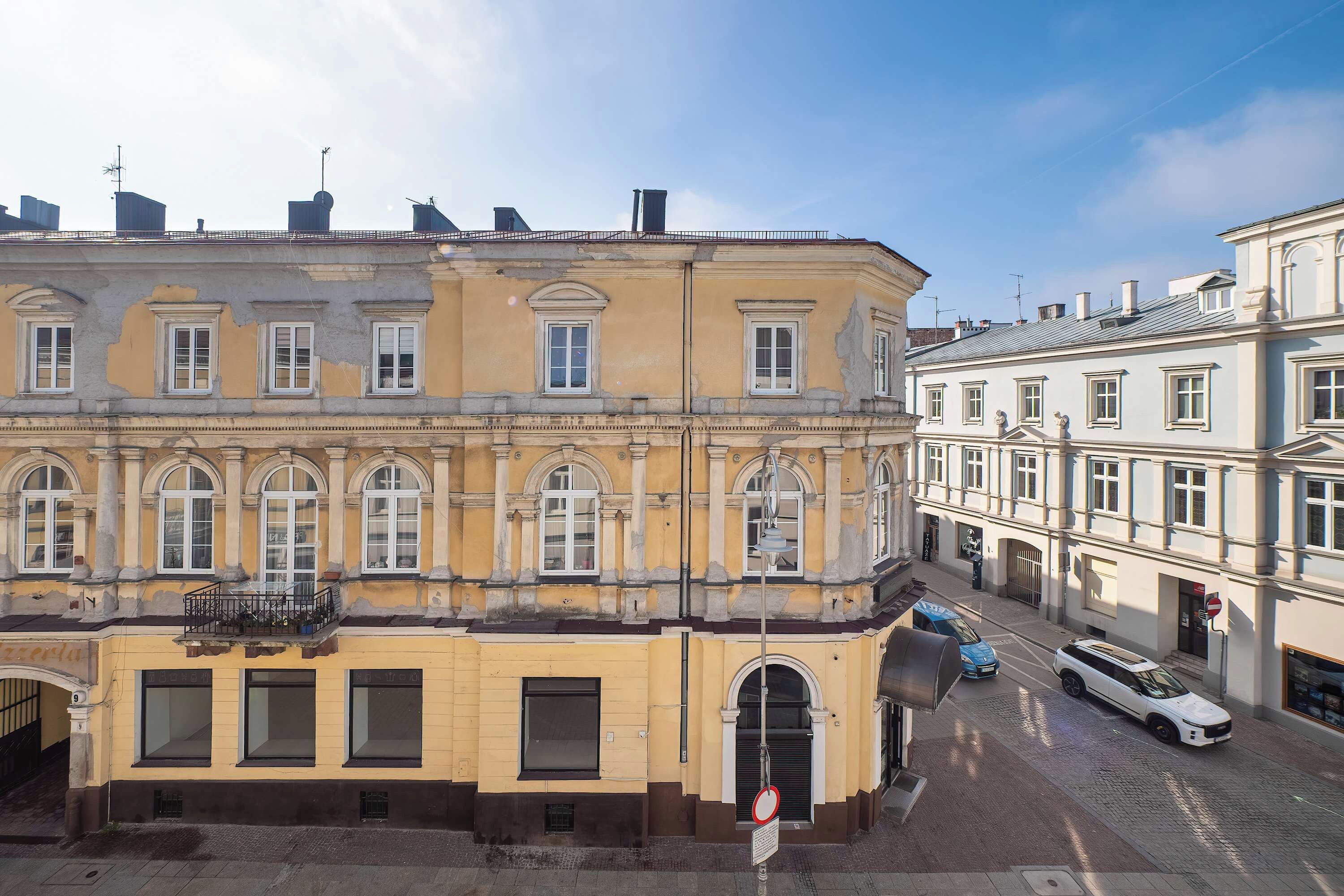 A historic building with multiple windows, a visible entrance, and a street in front.