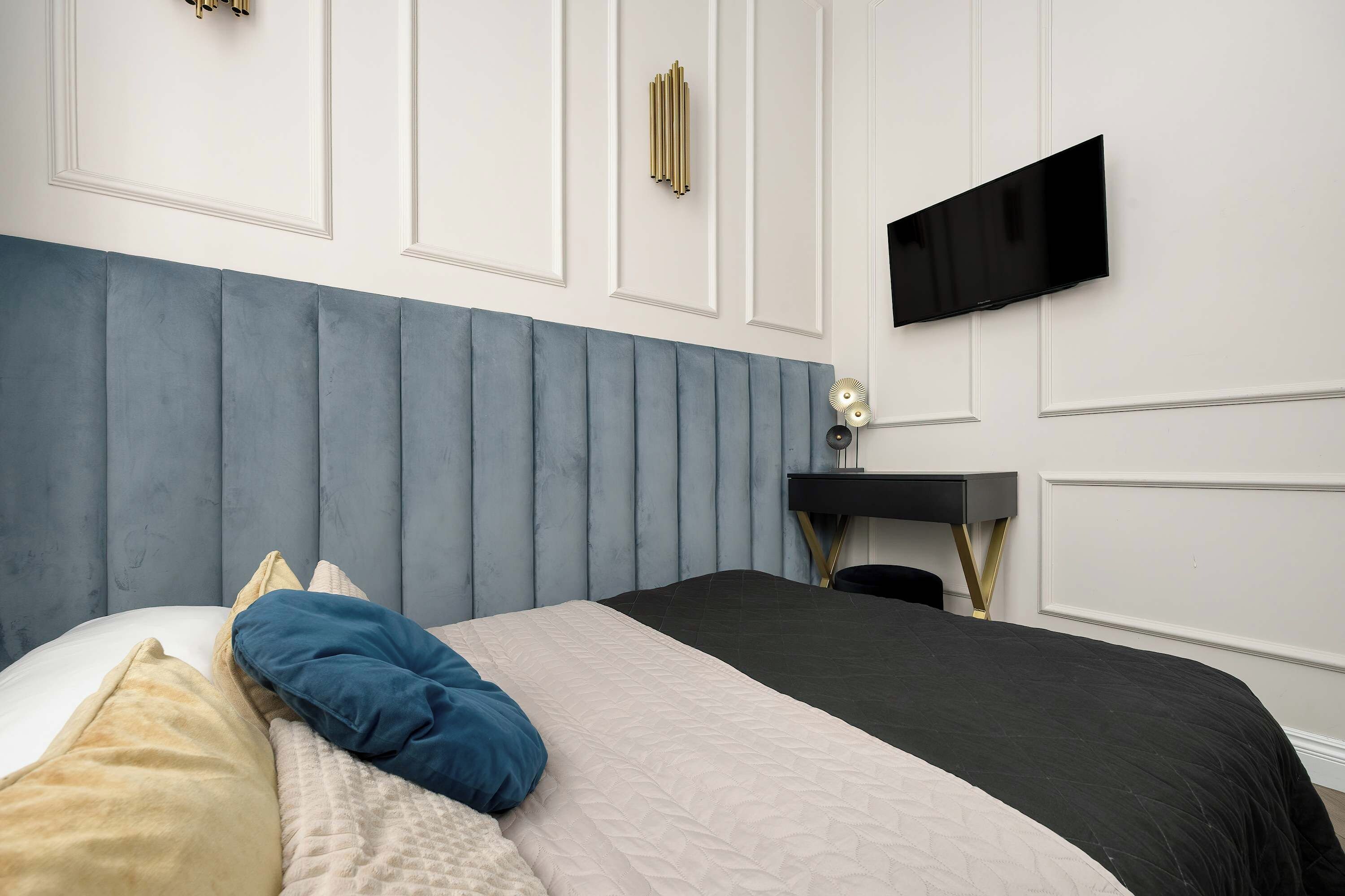 Une chambre à coucher comprenant un lit, un bureau et un téléviseur fixé au mur.