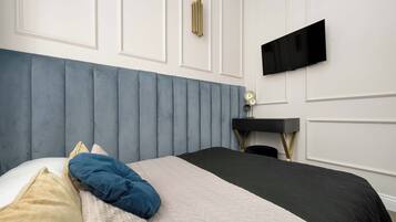 A bedroom with a bed, a desk, and a television mounted on the wall.