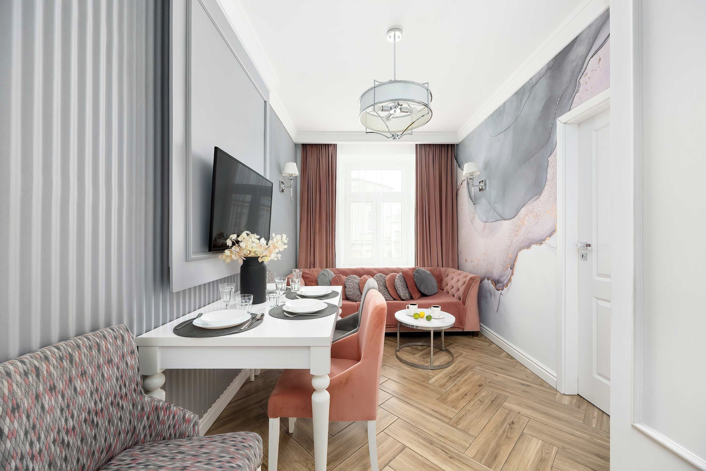 A modern dining area with a white table set for two, a sofa, and a decorative wall with a unique texture.