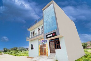 A two-story hotel with a modern design, featuring a prominent 'OYO hotel' sign, a balcony on the upper floor, and a large entrance door. - Hotel O Swarnim hotel (Neemrana)