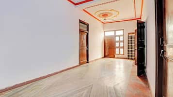A hallway with a wooden door, a checkered door, and a window with a view.