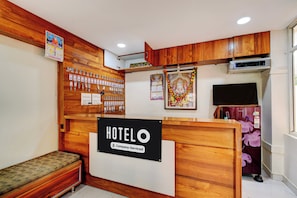 Ein Hotelrezeptionstresen mit einem Schild, das angibt, dass es sich um ein betrieblich betreutes Hotel handelt. An den Wänden befinden sich Holzpaneele, eine Bank und ein Wandkalender.