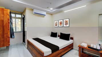 A modern bedroom with a wooden bed, a bedside table with a kettle, and a window with a curtain.
