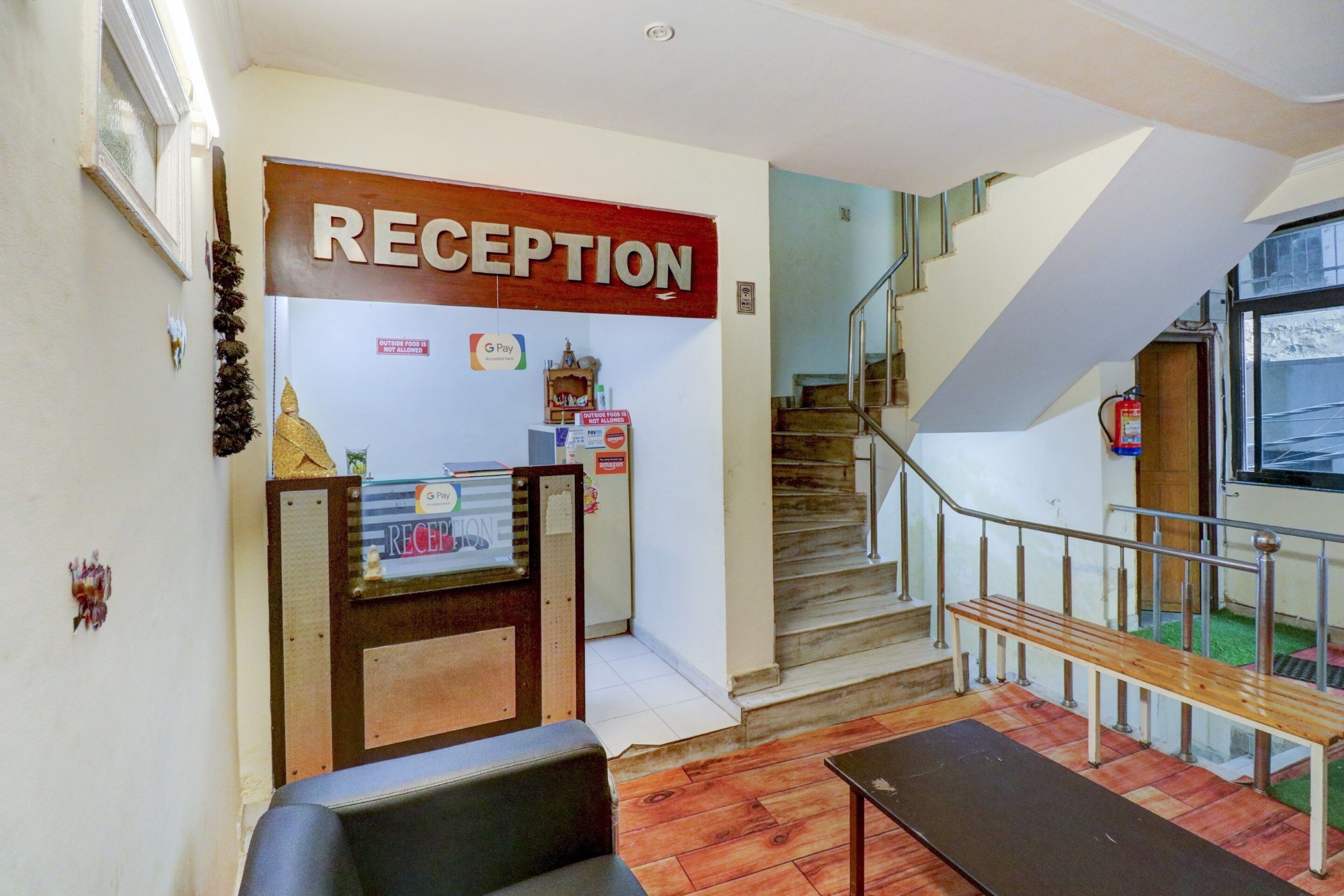 Un área de recepción con un letrero, una escalera y un banco.