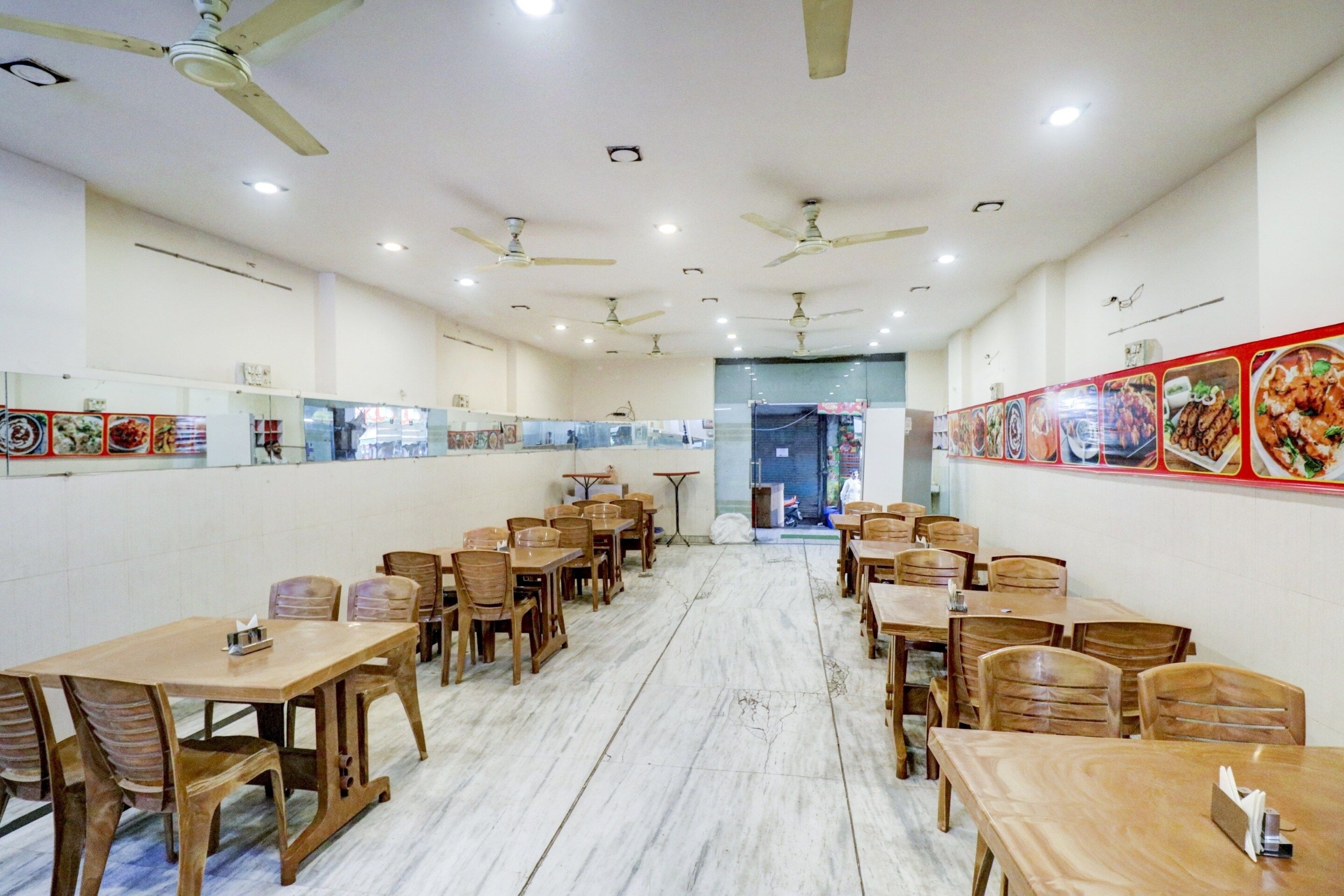 Interior de restaurante con varias mesas y sillas, ventiladores de techo y menús en las paredes.