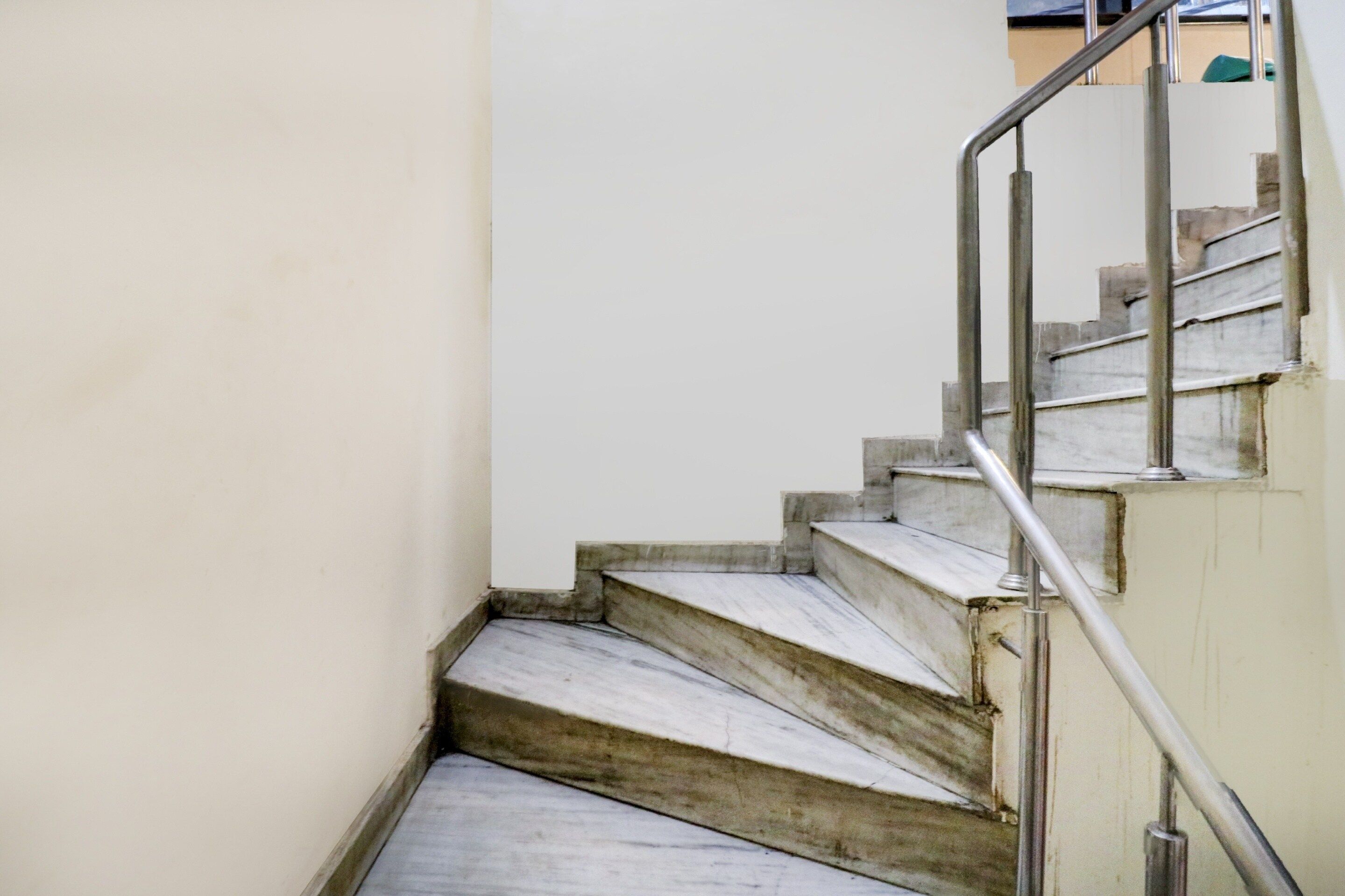 Una escalera con barandilla de metal y pared blanca.