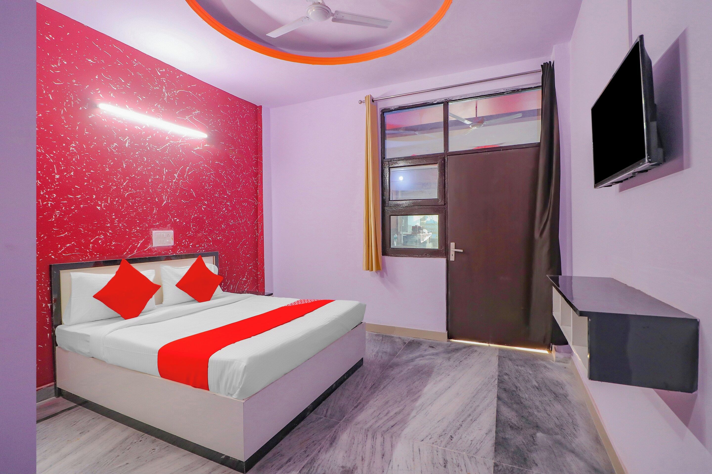 Une chambre à coucher avec un lit, une télévision, une fenêtre et un ventilateur de plafond.