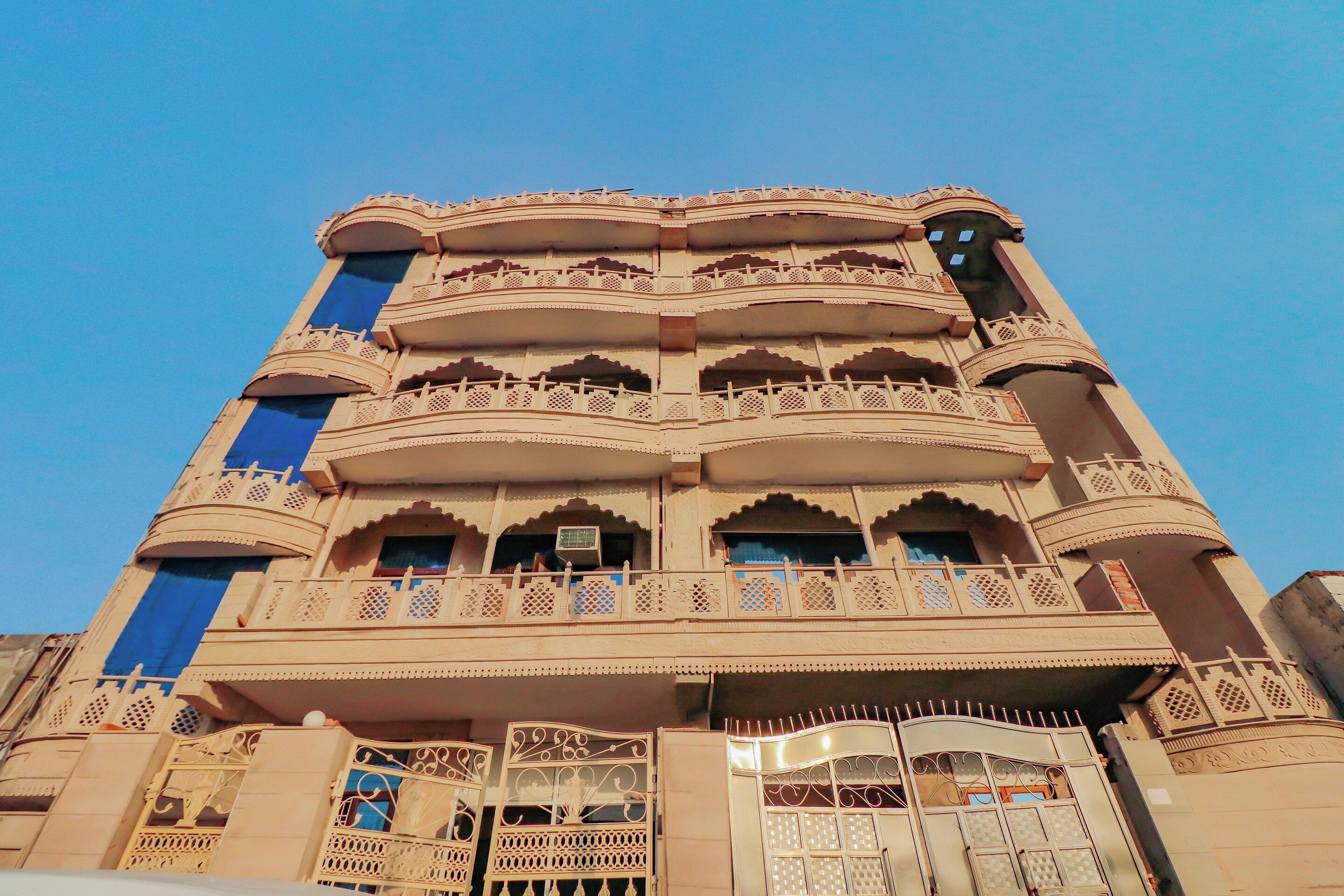 Un immeuble à plusieurs étages, doté de balcons richement décorés et d’une entrée centrale.
