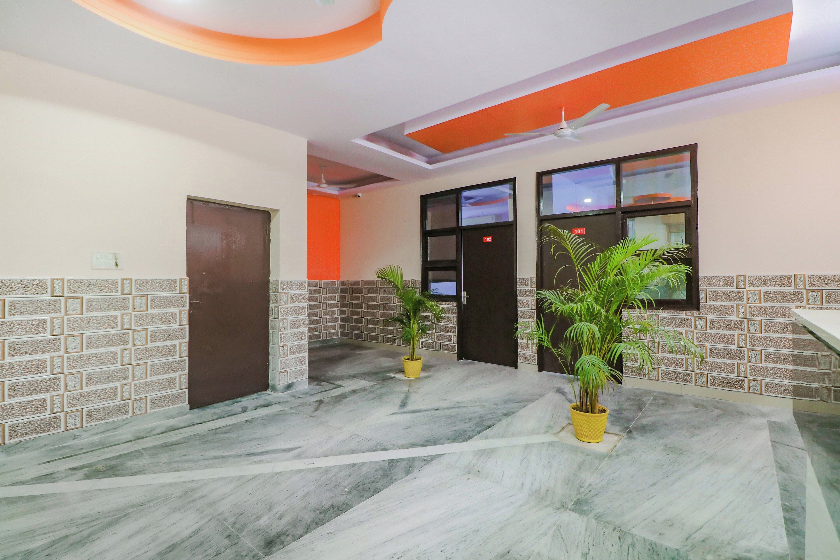Un'hall d'albergo con pavimento in marmo, una reception e due piante in vaso.
