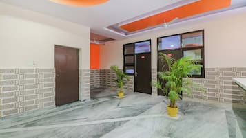 Un'hall d'albergo con pavimento in marmo, una reception e due piante in vaso.