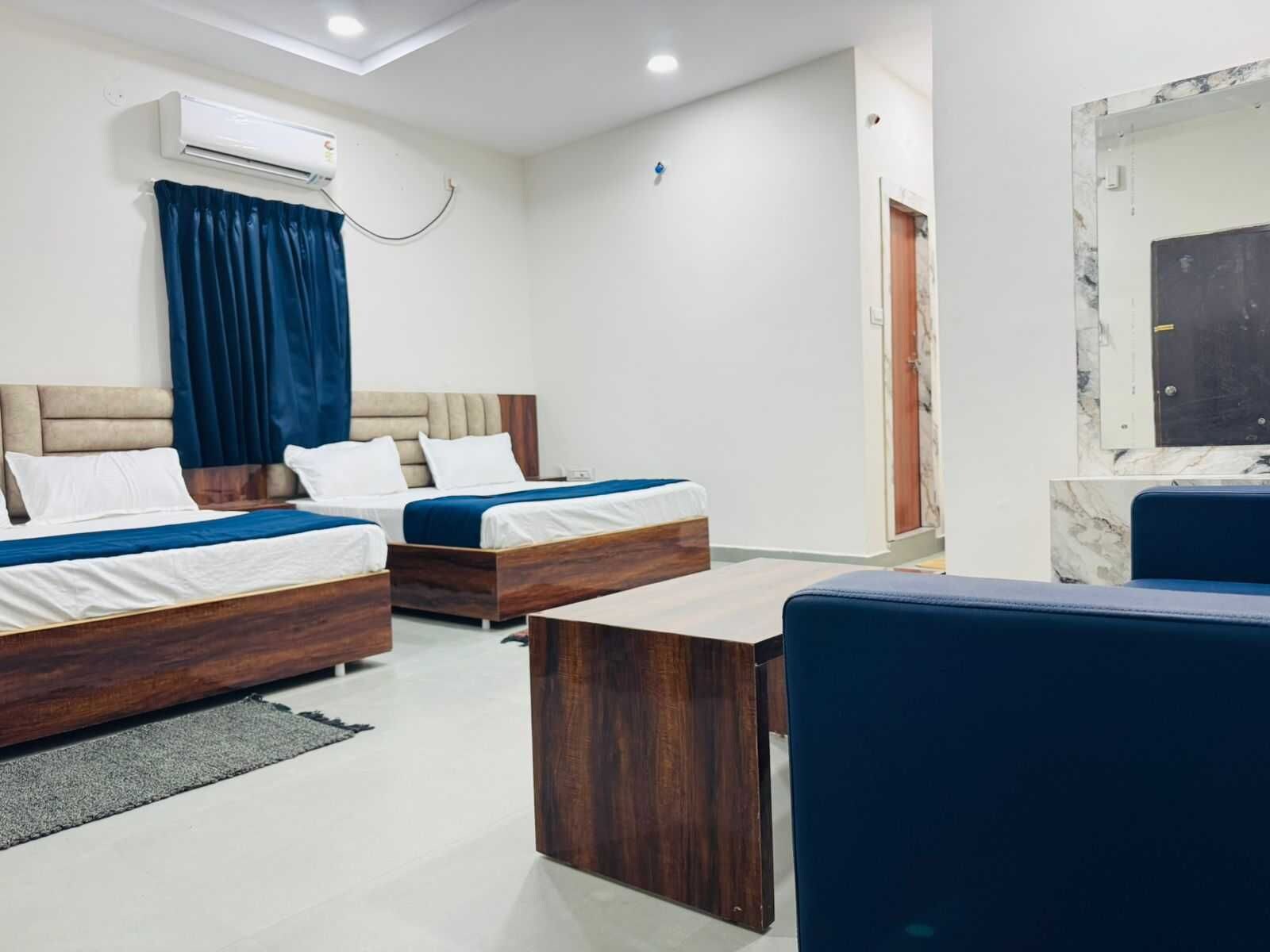 Habitación de hotel con dos camas, un escritorio, una silla, un equipo de aire acondicionado y una pared de mármol.
