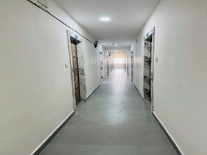A long, narrow hallway with doors on both sides, leading to individual rooms.