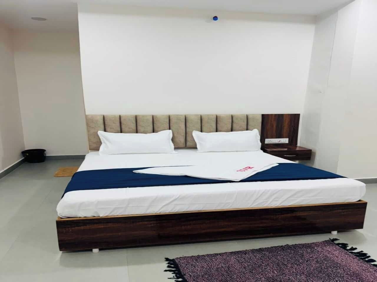 Un dormitorio con una cama, una mesita de noche, un cabecero de madera y una alfombra pequeña.