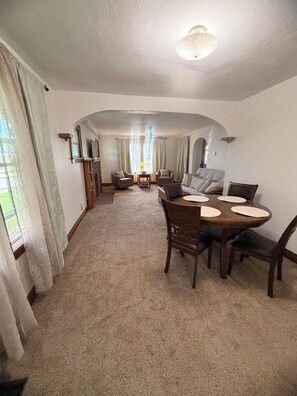 A living room with a fireplace, a dining area with a table and chairs, and a seating area with sofas.