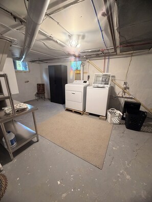 A laundry room with a washing machine, dryer, and a utility cart.