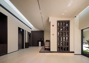 A modern interior with a central column, a staircase, and a glass door leading outside. - Zhangjiajie Yunfu Garden Hotel - Tianmen (Zhangjiajie)