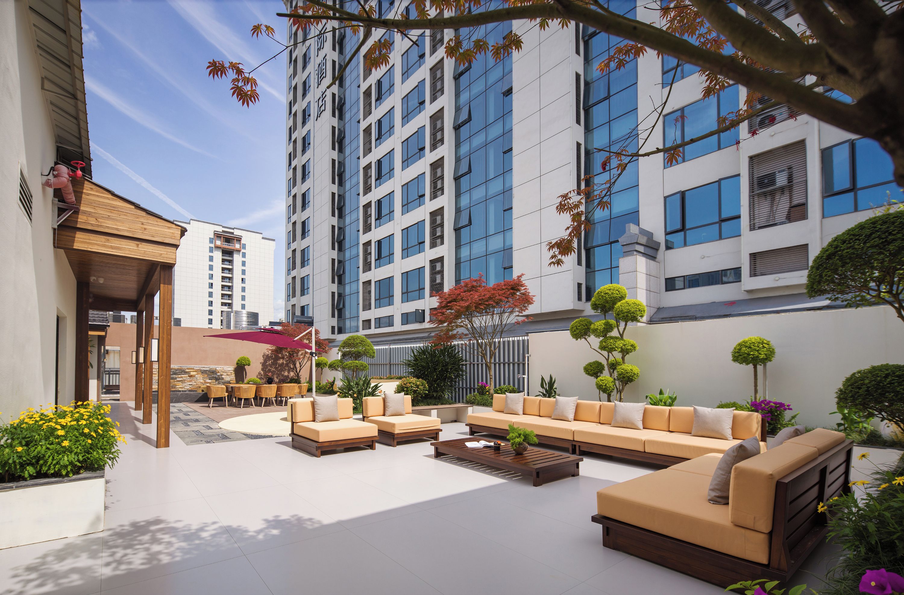 A modern outdoor lounge area with seating arrangements and a view of a high-rise building.
