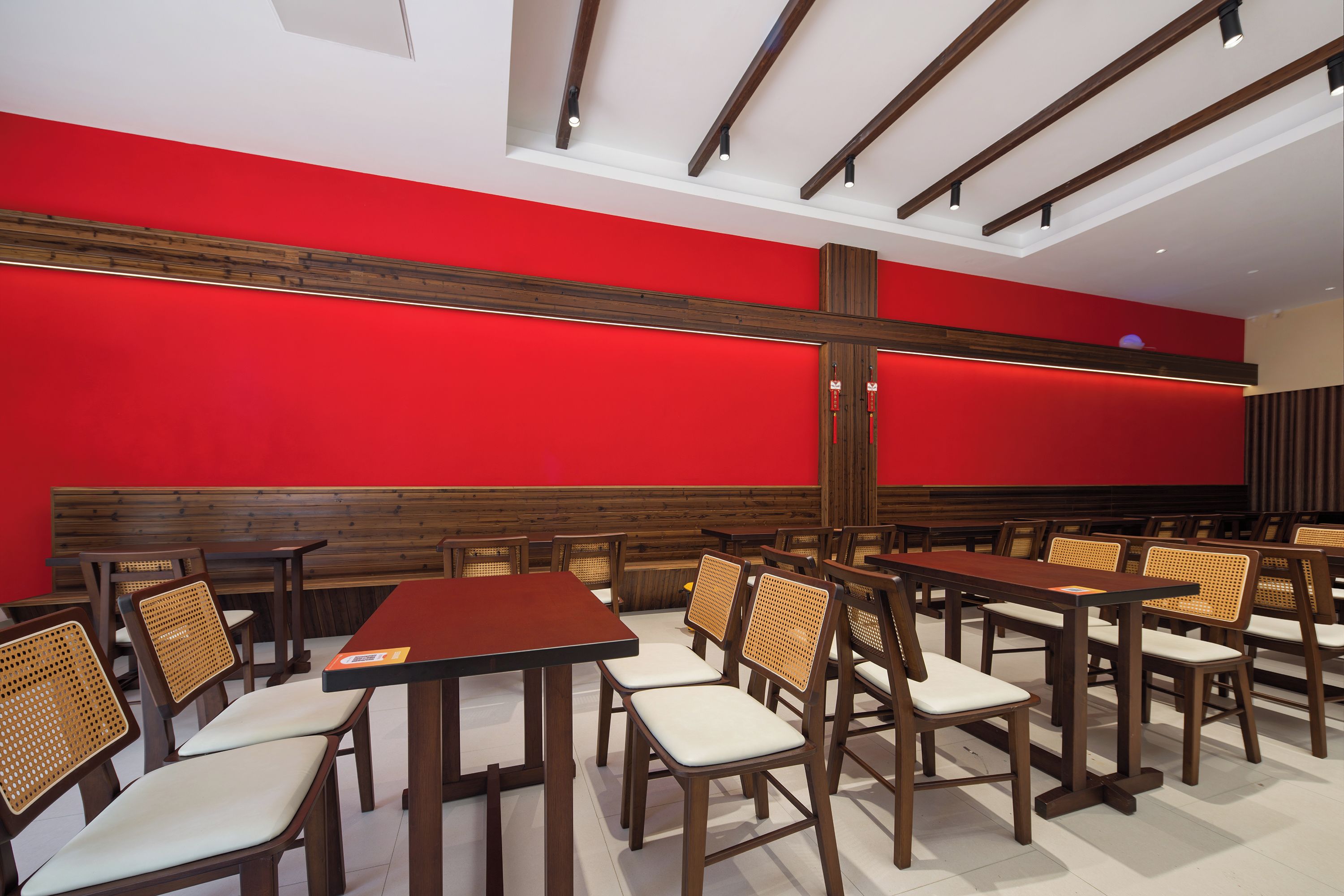 Interior de restaurante con paredes rojas, mesas y sillas de madera.