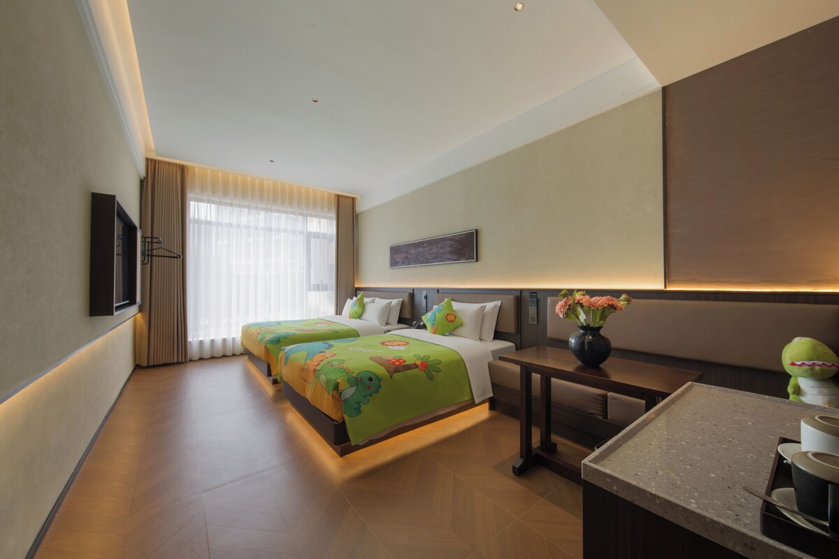 Een hotelkamer met een bed, nachtkastje en een klein bureau met stoel.