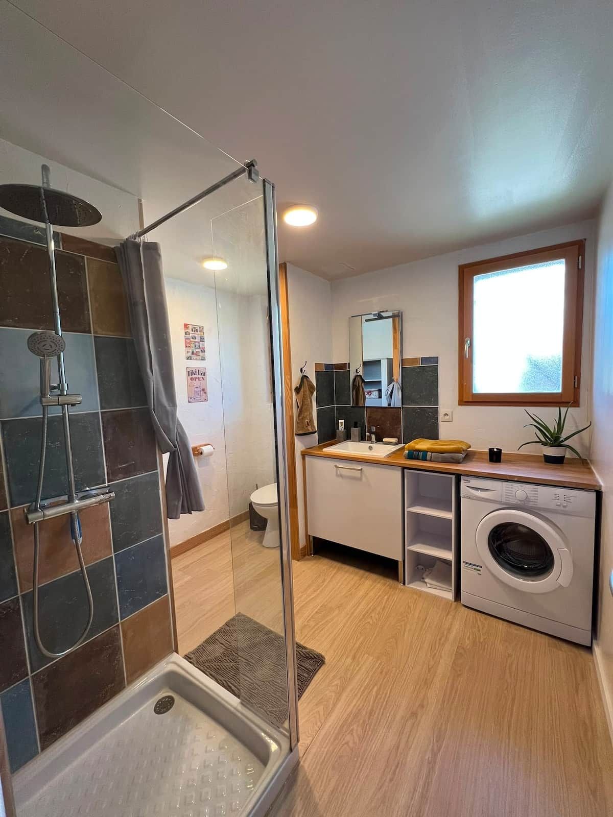 Une salle de bain moderne équipée d’une douche, de toilettes, d’un lavabo et d’un lave-linge encastré.