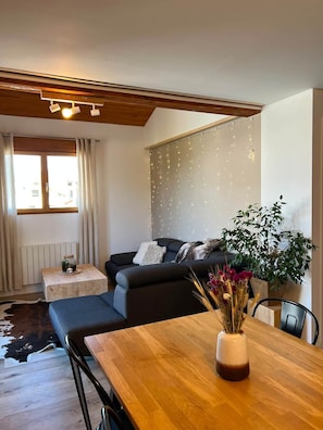 Ein modernes Wohnzimmer mit einer Couch, einem Couchtisch mit einer Vase und einem Esstisch mit Stühlen.
