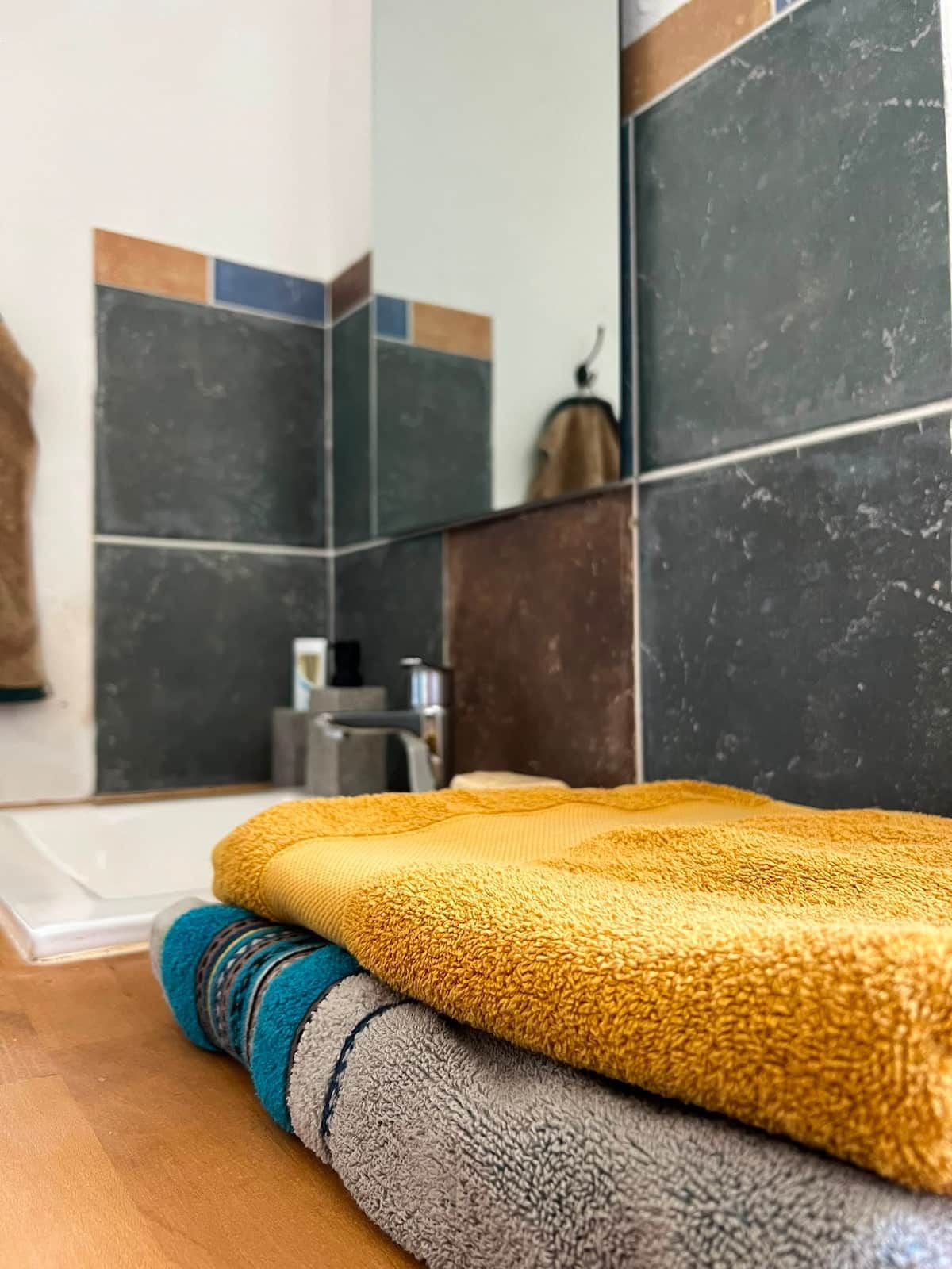 A bathroom with dark tiles and a towel rack.