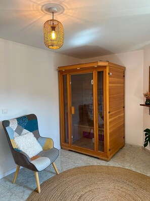 Una habitación con un armario de madera, un sillón estampado y una alfombra tejida.