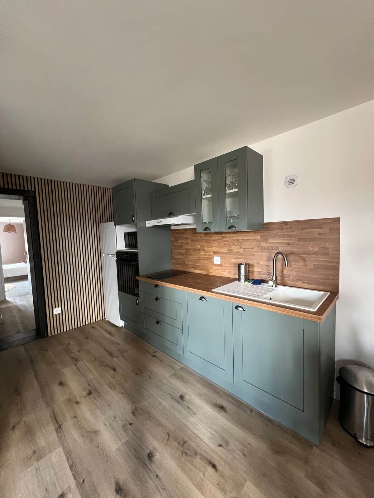 Une cuisine moderne avec un plancher en bois, des armoires bleu clair et un évier en acier inoxydable.