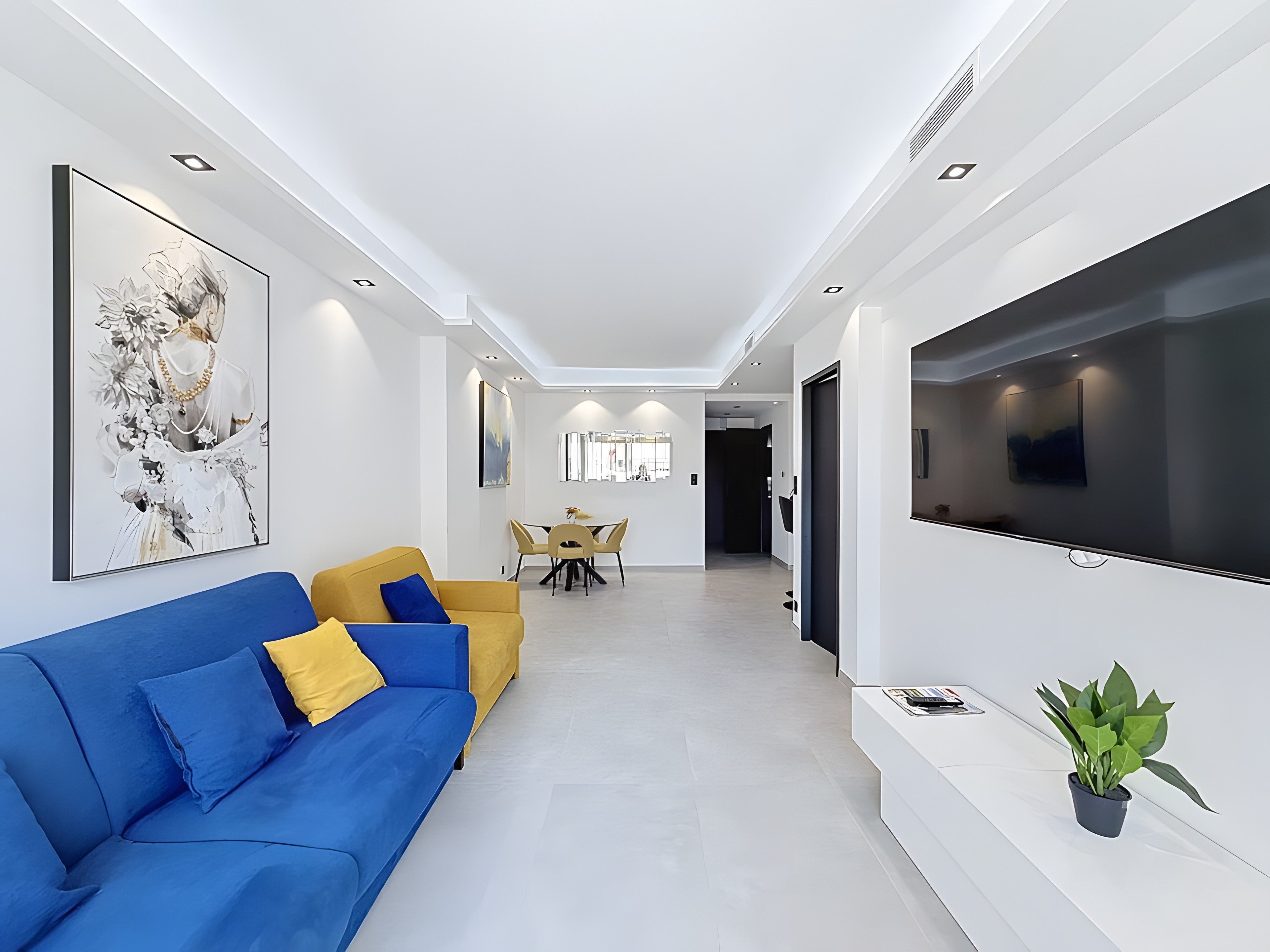A modern living room with a sofa, a flat-screen TV, and artwork on the walls.